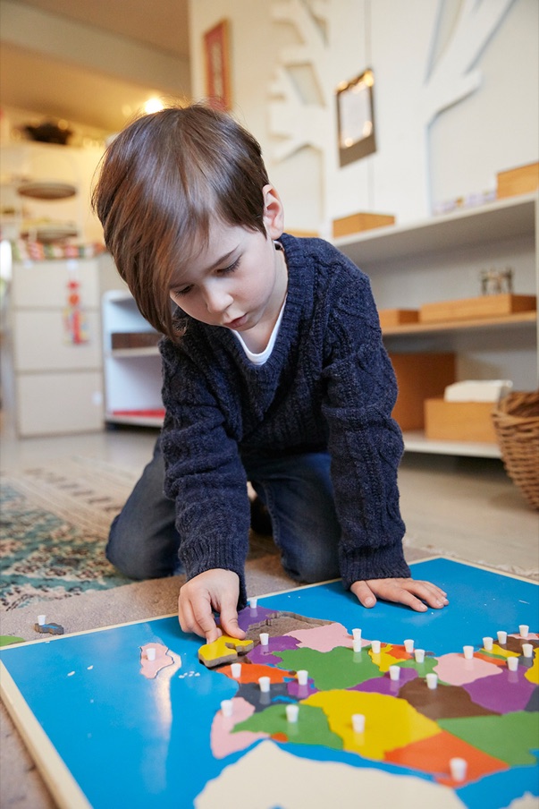 A child laying out a floor puzzle of Australia