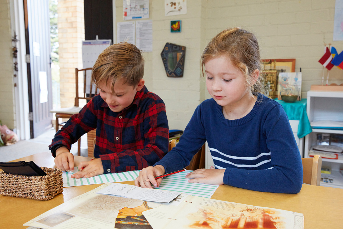 Two children working side by side at a classroom table